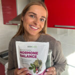 Mergina žiūri į kamerą laikydama Everjuno produktus ir šypsosi